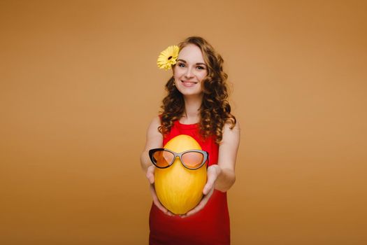 Portrait of a happy young woman holding a melon with glasses. Melon with a smile.