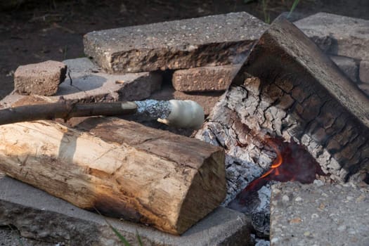 baking bread by heating bread dough on a stick over the campfire