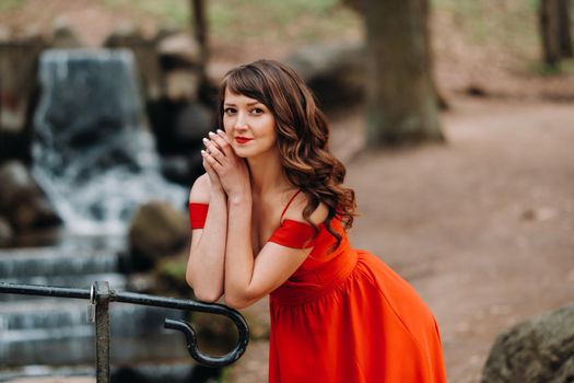 Spring Portrait of a laughing girl in a long red dress with long hair walking in the Park in the woods