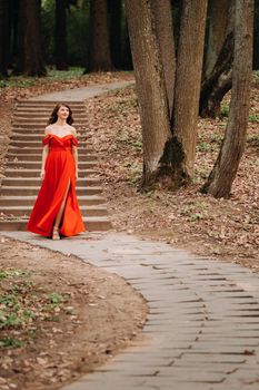 Spring Portrait of a laughing girl in a long red dress with long hair walking in the Park in the woods