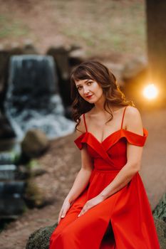 Spring Portrait of a laughing girl in a long red dress with long hair walking in the Park in the woods