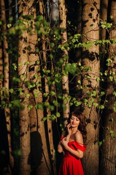 Spring Portrait of a laughing girl in a long red dress with long hair walking in the Park in the woods