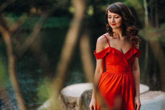 Spring Portrait of a laughing girl in a long red dress with long hair walking in the Park in the woods