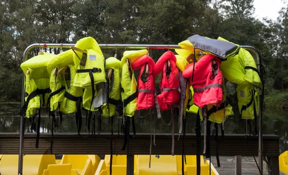 rack of red and yellow life jackets by a water