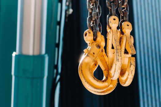 The hooks of the mobile crane near the glass of high buildings.Lots of hooks hanging from chains suspended from a crane.