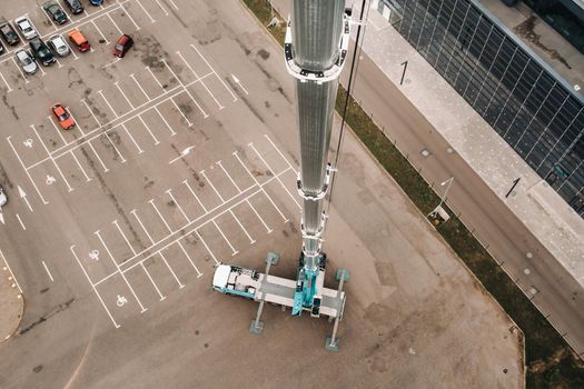 view from the height of the tallest car crane, which is open in the Parking lot near the glass building in the city and ready to work. the highest mobile crane is deployed on the site. the height of the arrow is 80 meters
