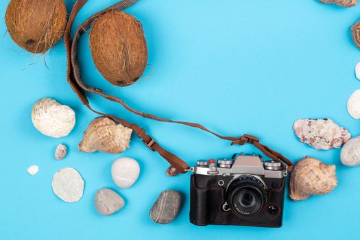 camera,coconuts and shells on a blue background.Background for the traveler.