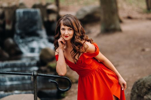 Spring Portrait of a laughing girl in a long red dress with long hair walking in the Park in the woods