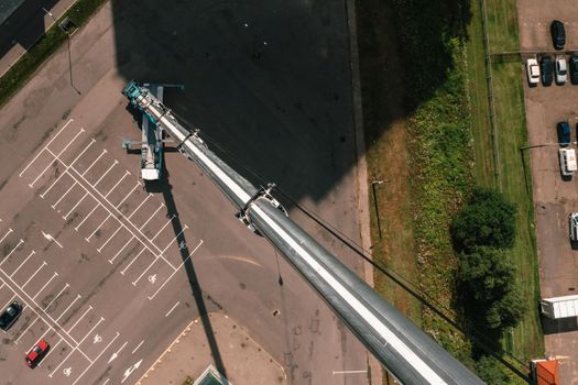 view from the height of the Car heavy crane that stands open in the Parking lot and ready to work. the highest truck crane is deployed on the site. the height of the boom is 80 meters.