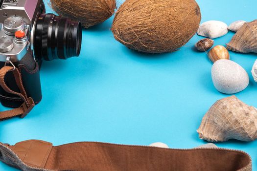 camera,coconuts and shells on a blue background.Background for the traveler.