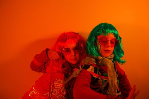 Little girls wearing a colorful wig and heart-shaped sunglasses posed for a photo shooting on the disco light background