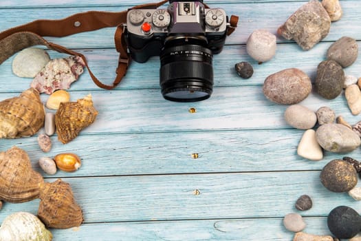 camera and seashells on a blue wooden background.Marine theme.