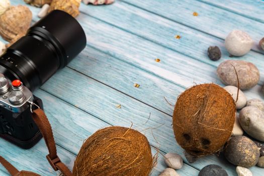 camera,coconuts and shells on a blue wooden background.Marine theme.