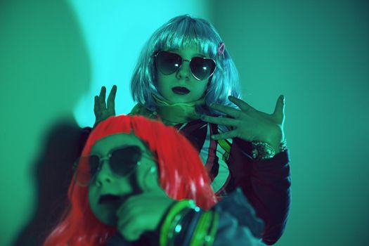 Little girls wearing a colorful wig and heart-shaped sunglasses posed for a photo shooting on the disco light background