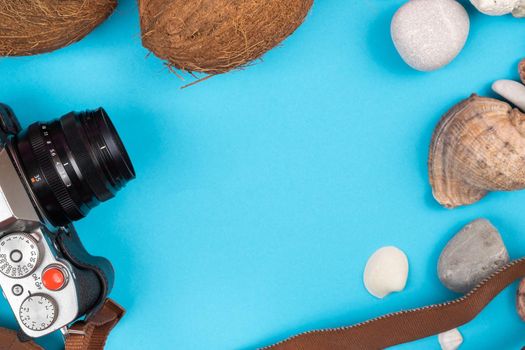 camera,coconuts and shells on a blue background.Background for the traveler.
