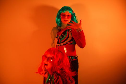 Little girls wearing a colorful wig and heart-shaped sunglasses posed for a photo shooting on the disco light background