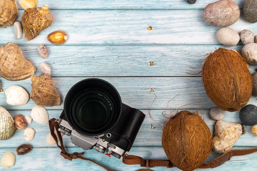 camera,coconuts and shells on a blue wooden background.Marine theme.