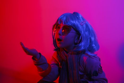 Little girl blowing kiss wearing a colorful wig and heart-shaped sunglasses posed for a photo shooting on the disco light background