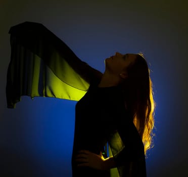 Portrait against the gold light of a young beautiful woman posing on blue background