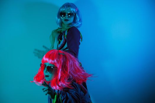 Little girls wearing a colorful wig and heart-shaped sunglasses posed for a photo shooting on the disco light background