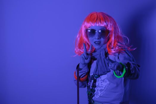 Child wearing a pink wig and heart-shaped sunglasses posed for a photo shooting on the disco light background