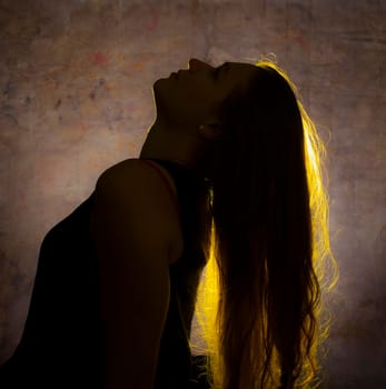Portrait against the gold light of a young beautiful woman
