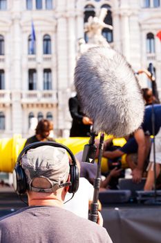 Behind the scene. Sound recorder with microphone, boom mic and headphones filming movie scene on outdoor location