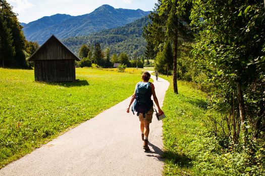 Young woman with backpack hiking along the path in the Slovenian countryside. Bohinj