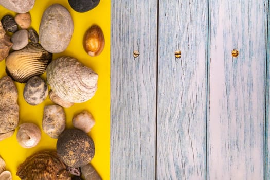 stones and shells on a blue wooden background and a yellow background.Marine theme.
