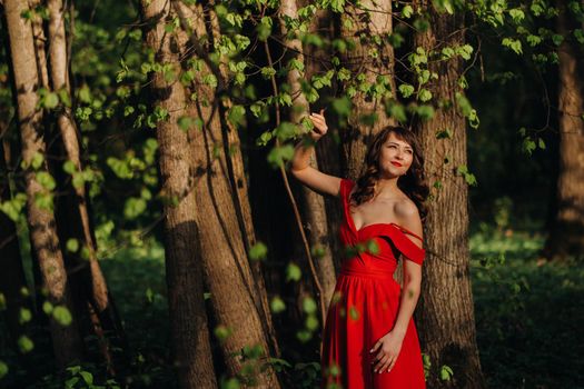 Spring Portrait of a laughing girl in a long red dress with long hair walking in the Park in the woods