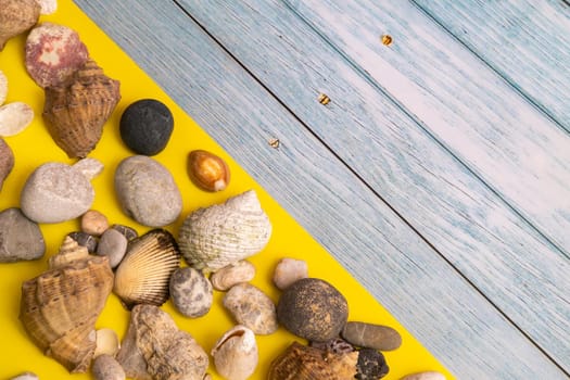 stones and shells on a blue wooden background and a yellow background.Marine theme.