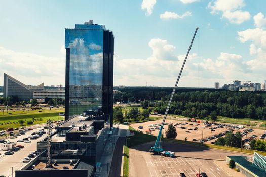 a view from the height of the tallest car crane, which is open in the Parking lot near the glass building in the city and ready to work. the highest mobile crane is deployed on the site. the height of the arrow is 80 meters