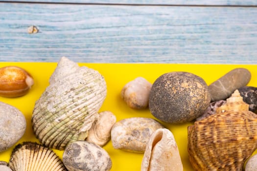 stones and shells on a blue wooden background and a yellow background.Marine theme.