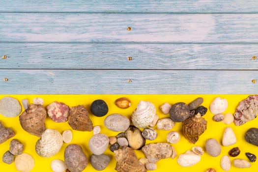 stones and shells on a blue wooden background and a yellow background.Marine theme.