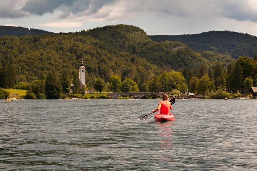 Girl kayaking in the scenic Bohinj lake, Slovenia