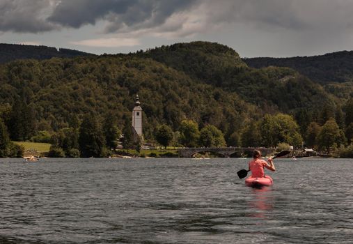 Girl kayaking in the scenic Bohinj lake, Slovenia