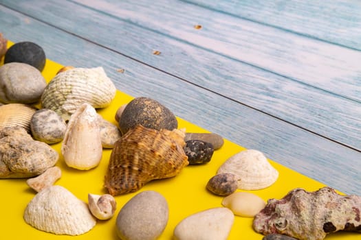 stones and shells on a blue wooden background and a yellow background.Marine theme.