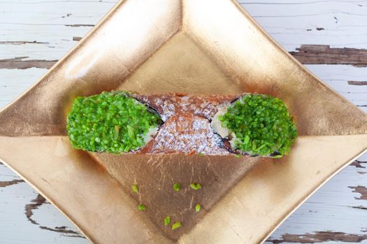 Cannolo, the typical Sicilian pastry on a gold plate