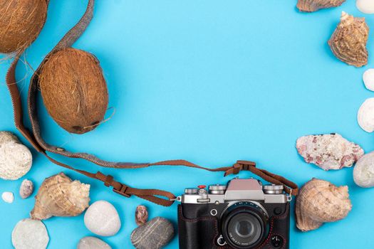 camera,coconuts and shells on a blue background.Background for the traveler.