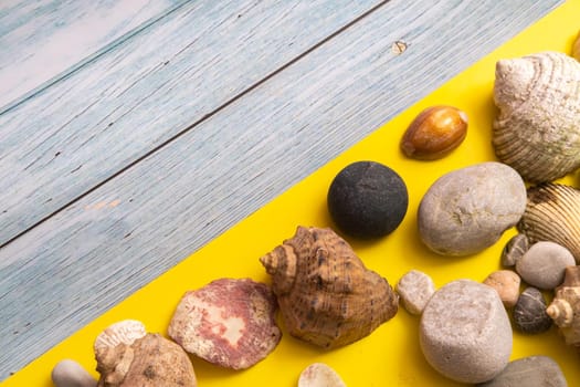 stones and shells on a blue wooden background and a yellow background.Marine theme.