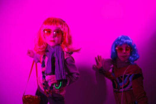 Little girls wearing a colorful wig and heart-shaped sunglasses posed for a photo shooting on the disco light background