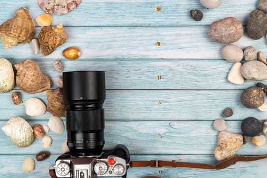 camera and seashells on a blue wooden background.Marine theme.