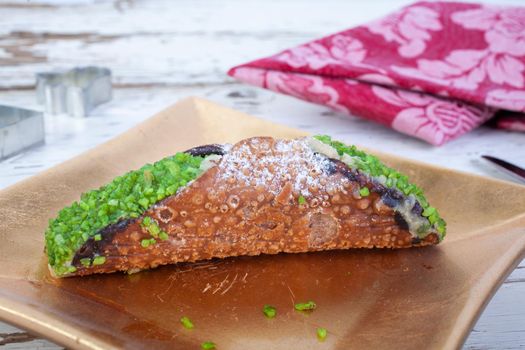 Cannolo, the typical Sicilian pastry on a gold plate