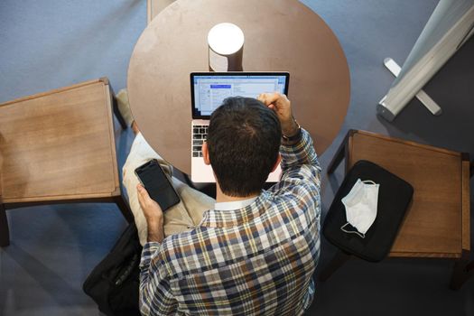 Top view of a man sitting at the table working with his notebook