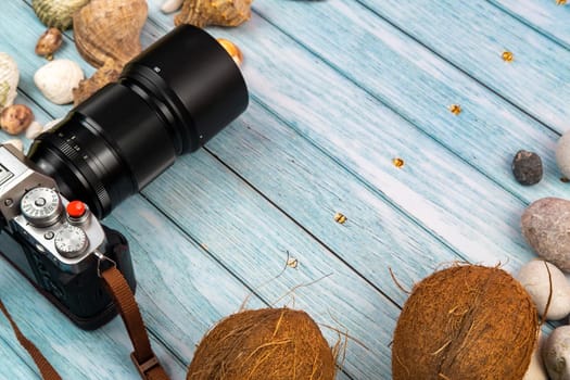 camera,coconuts and shells on a blue wooden background.Marine theme.