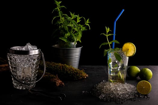 Delicious refreshing mint cocktail called mojito with rum and lime, cold drink or beverage with ice on black background