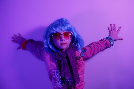 A glamour little girl posing for a photo portrait while wearing a colorful wig on purple background