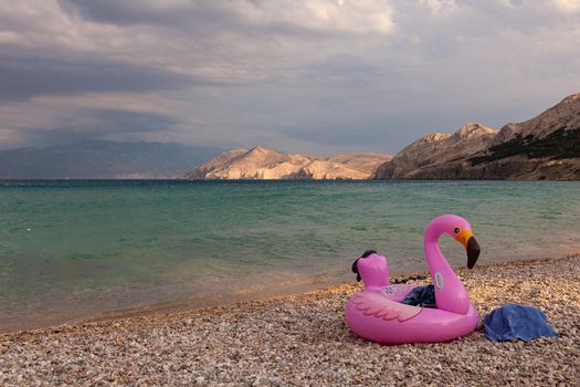 View of a swimming inflatable ring with flamingo design on the beach of Baska, Croatia