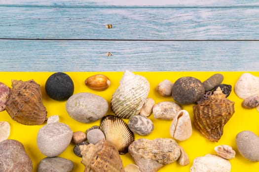 stones and shells on a blue wooden background and a yellow background.Marine theme.