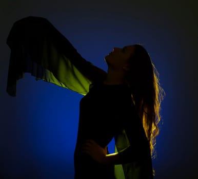 Portrait against the gold light of a young beautiful woman posing on blue background